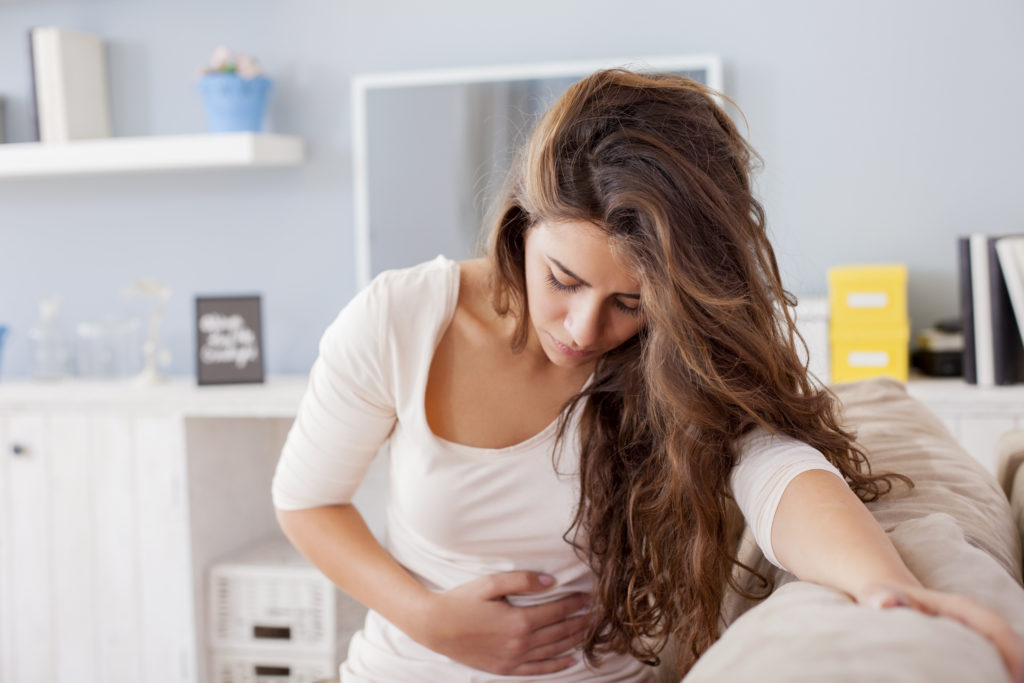 Junge Frau wird von Beschwerden einer Magen-Darmgrippe geplagt