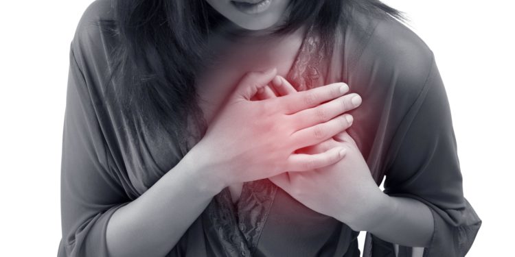 Frau fasst sich mit ihren Händen an den schmerzenden Brustkorb