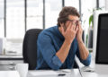 Mann im Büro reibt sich die müden Augen.