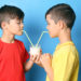 Zwillingsbrüder trinken mit Strohhalmen Milch aus einem gemeinsamen Glas