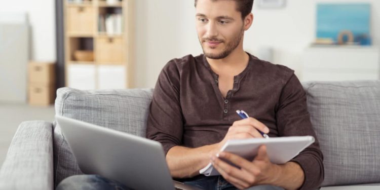 Mann mit Laptop macht sich auf einem Block Notizen