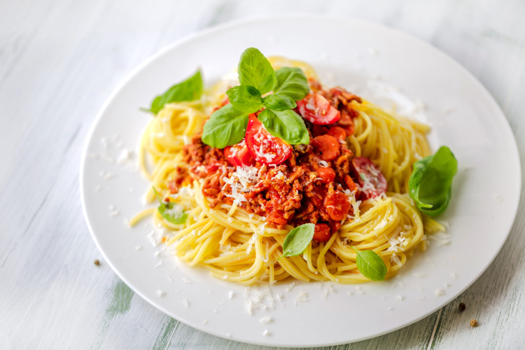 Ein Teller Pasta mit Soße, Basilikum und Parmesan