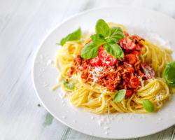 Ein Teller Pasta mit Soße, Basilikum und Parmesan