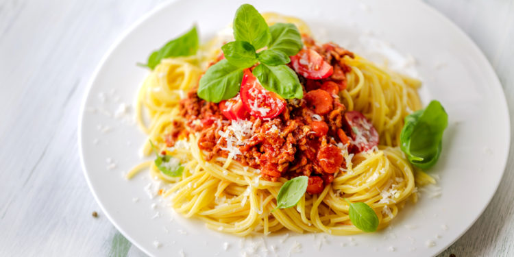 Ein Teller Pasta mit Soße, Basilikum und Parmesan