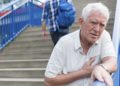 Ein älterer Mann auf einer Treppe fasst sich ans Herz
