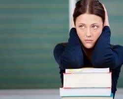 Frau stützt ihre Arne auf einen Stapel Bücher und guckt besorgt