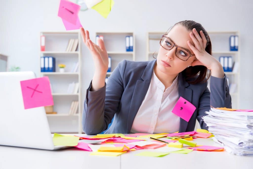 Genervte Frau am Schreibtisch mit Post-it-Zetteln