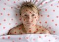 Frau im Bett umkreist von roten Punkten.