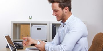 Ein Mann im Büro hat Schmerzen im Unterarm.