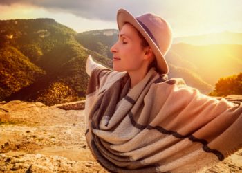 Frau in bergiger Landschaft streckt ihre Arme aus