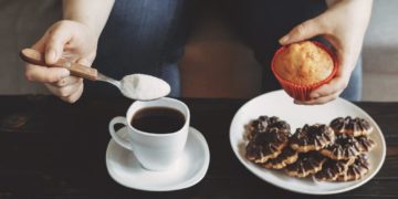 Sugar addiction, unhealthy lifestyle, weight gain, dietary, healthcare and medical concept. Cropped portrait of woman pouring sugar into coffee cup and eating sugary food