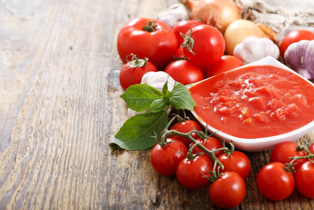 Frische Tomaten, Zwiebeln, Knoblauch und eine daraus zubereitete Tomatensoße