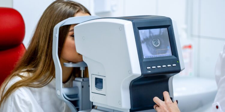 Eine Augenärztin betrachtet das Auge einer Patientin über einen Monitor.