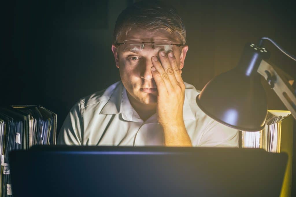 Mann reibt sich vor dem Computer seine müden Augen