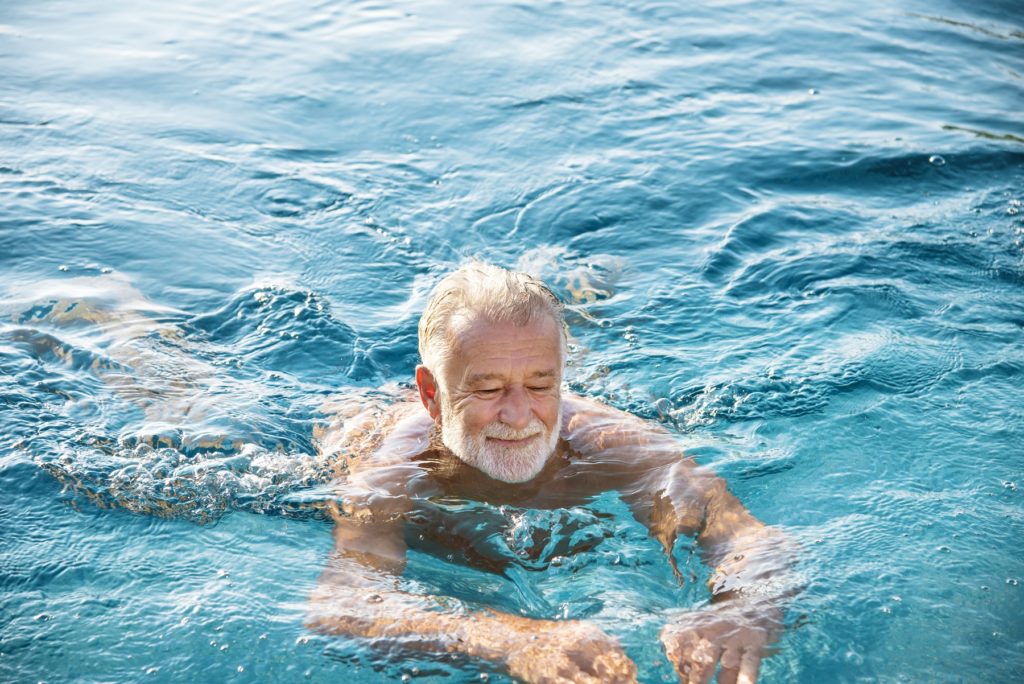 Älterer Mann schwimmt in einem Gewässer