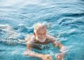 Älterer Mann schwimmt in einem Gewässer