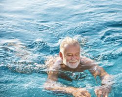 Älterer Mann schwimmt in einem Gewässer