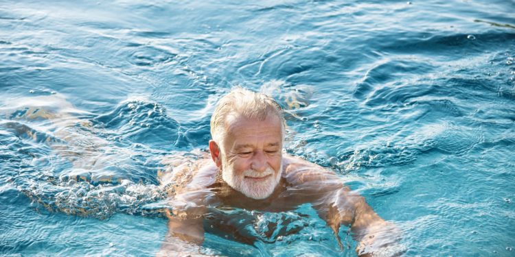 Älterer Mann schwimmt in einem Gewässer