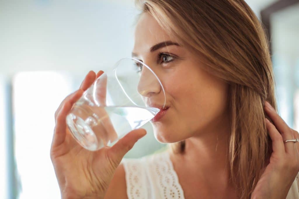 A woman drinks a glass of water
