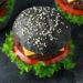 Mit Aktivkohle versetzte Lebensmittel wie Burger liegen im Trend. Experten raten jedoch von den schwarzen Speisen ab. Denn sie können die Wirkung von Medikamenten beeinträchtigen. (Bild: grinchh/fotolia.com)