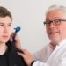Arzt untersucht das Ohr eines Jugendlichen