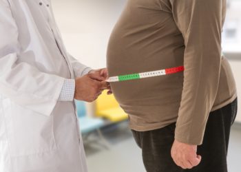 Arzt misst bei einem übergewichtigen Mann den Bauchumfang