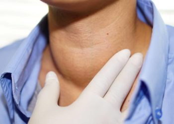 Frau fasst sich an den geschwollenen Hals.