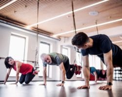 Mehrere Senioren trainieren im Fitnessstudio mit einem jungen Trainer