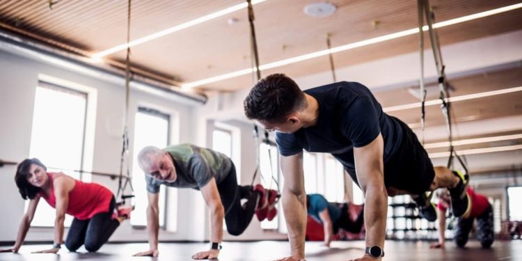 Mehrere Senioren trainieren im Fitnessstudio mit einem jungen Trainer