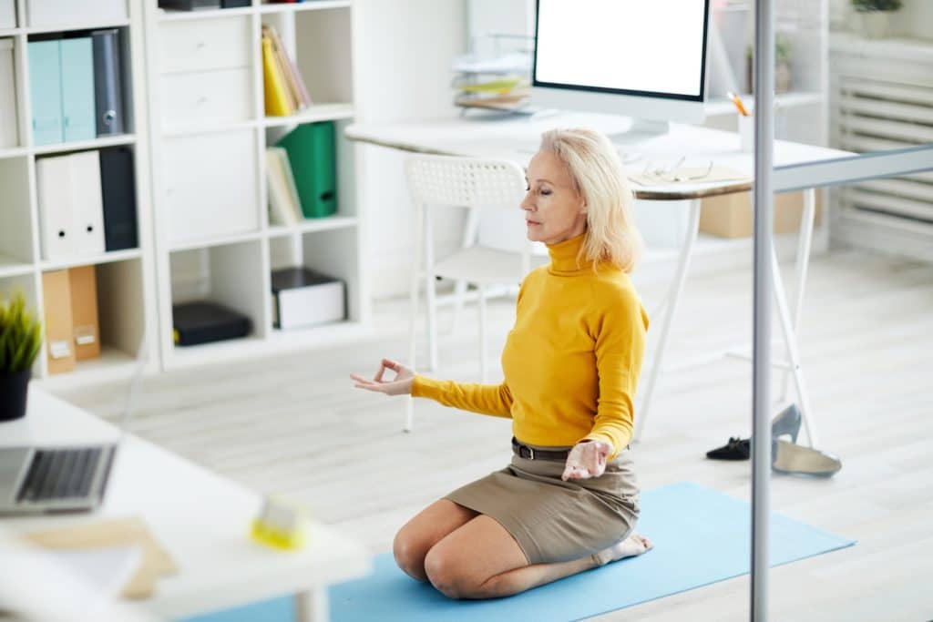 Frau praktiziert Yoga im Büro