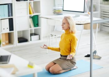 Frau praktiziert Yoga im Büro