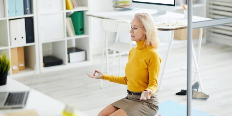 Frau praktiziert Yoga im Büro