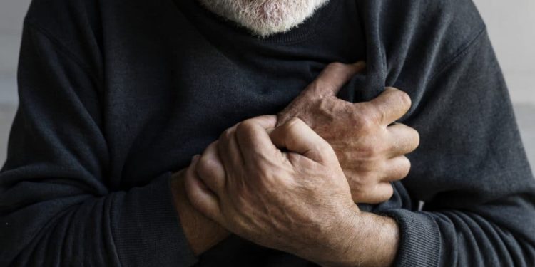 Älterer Mann hält sich die Hände an die schmerzende Brust