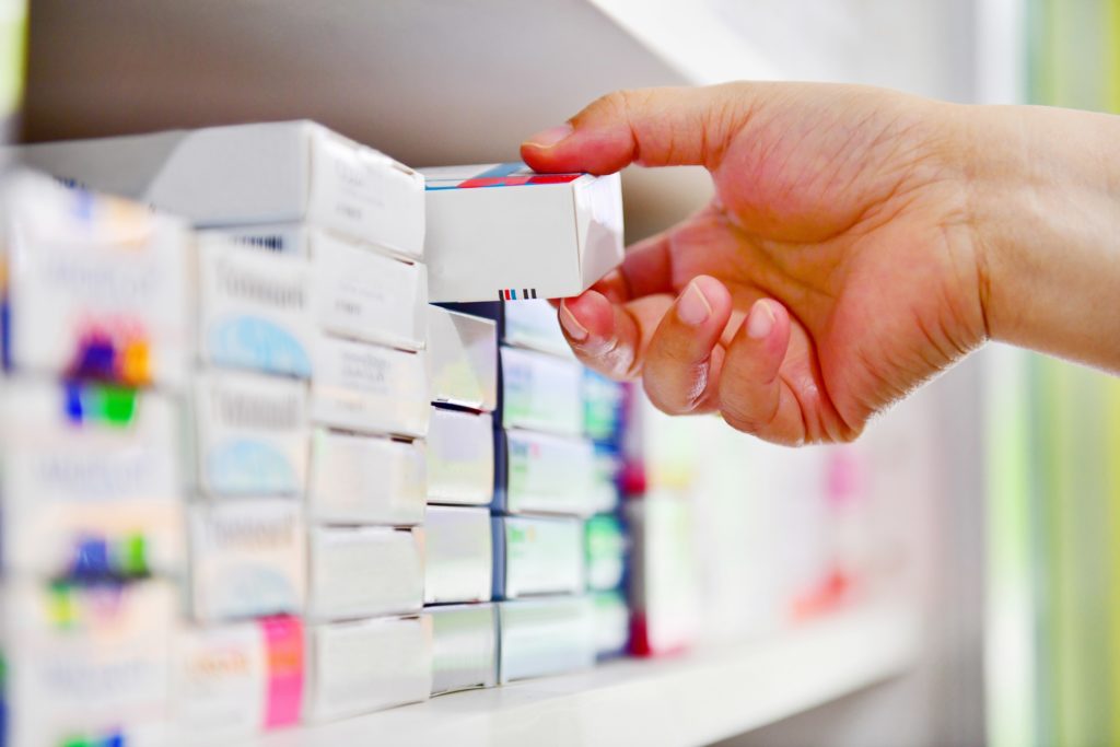 Apotheker nimmt eine Medikamentenpackung aus dem Regal