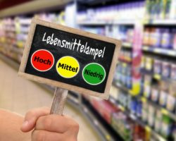 Schiefertafel mit einer Lebensmittelampel vor einem unscharfen Frischeregal im Supermarkt