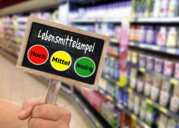 Schiefertafel mit einer Lebensmittelampel vor einem unscharfen Frischeregal im Supermarkt