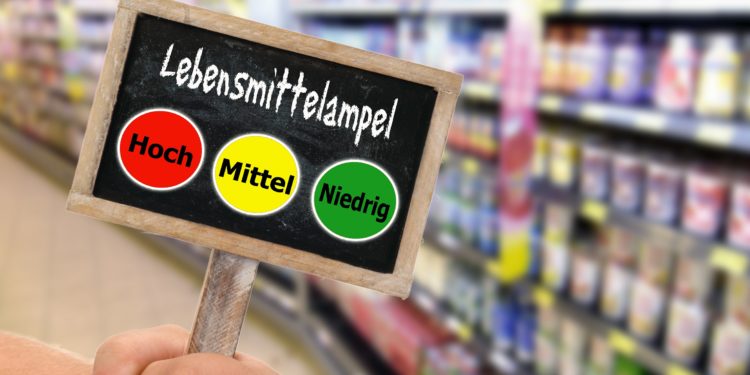 Schiefertafel mit einer Lebensmittelampel vor einem unscharfen Frischeregal im Supermarkt