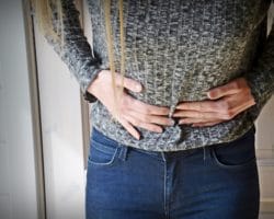Junge Frau hält sich den Bauch vor Schmerzen