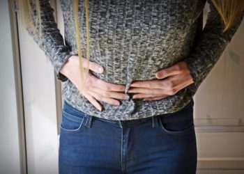 Junge Frau hält sich den Bauch vor Schmerzen