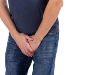 Mann fasst sich an den Genitalbereich