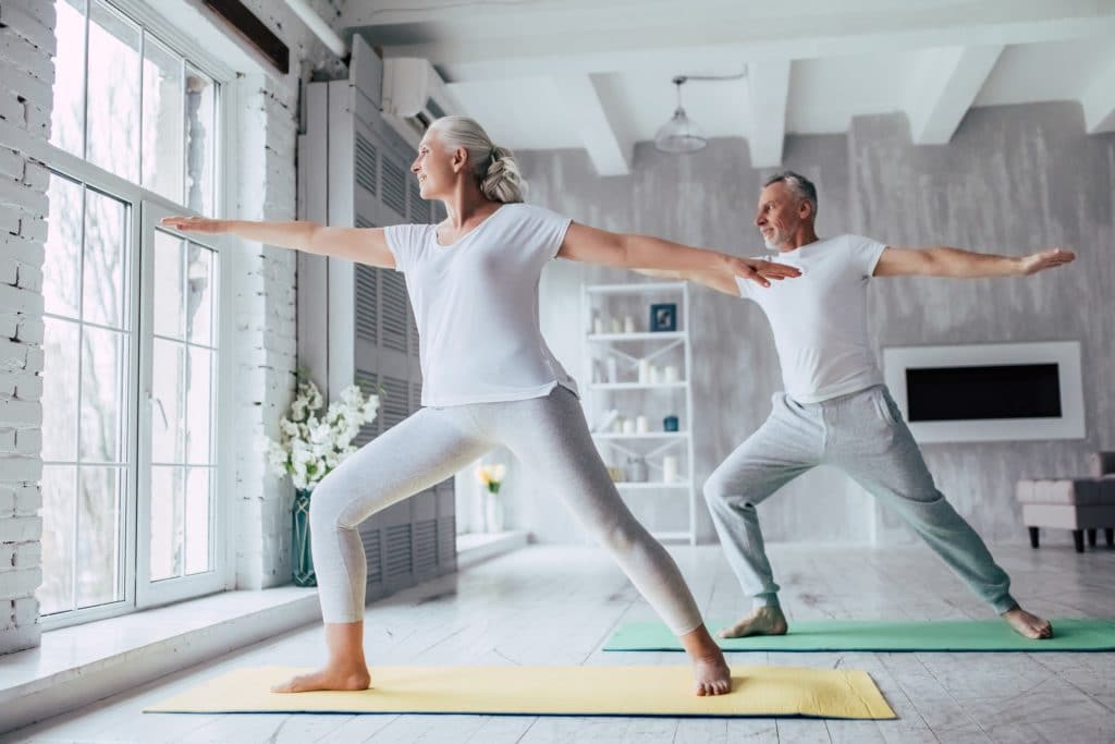 Ein älteres Paar macht Yoga daheim