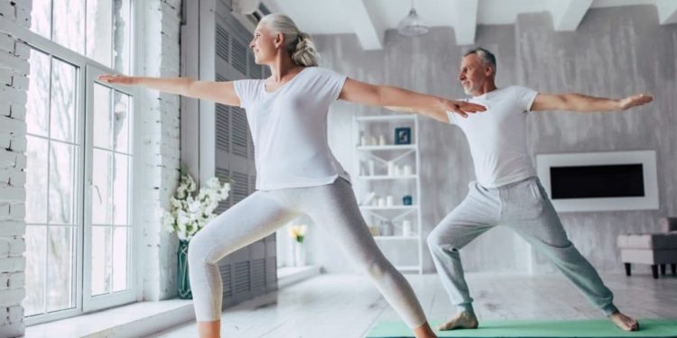Ein älteres Paar macht Yoga daheim