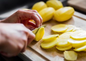 Mann schneidet Kartoffeln in Scheiben