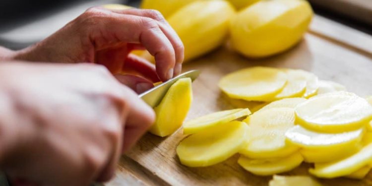 Mann schneidet Kartoffeln in Scheiben