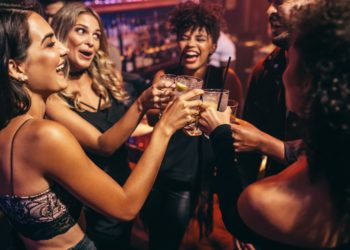 Eine Gruppe junger Personen stoßen in einem Nachtclub an