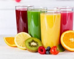4 Gläser mit Säften in unterschiedlichen Farben und Obst