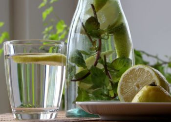 Karaffe mit Wasser, Zitronenscheiben und Minze sowie ein Glas