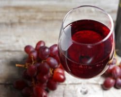 Rote Trauben und ein Glas Rotwein auf einem Holztisch