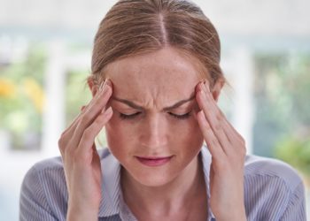 Frau fasst sich an die Schläfen