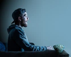 Seitenansicht eines Mannes mit geöffnetem Mund und Popcorn vor dem TV